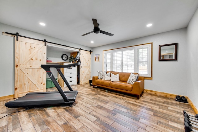 workout room featuring wood-type flooring, a barn door, and ceiling fan