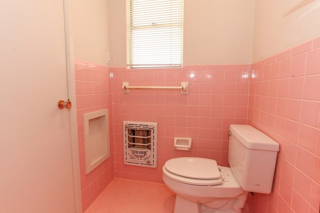 1900 Goliad St, Big Spring, TX 79720 - bathroom featuring heating unit, tile walls, toilet, and a wainscoted wall