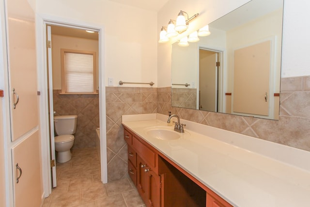 1900 Goliad St, Big Spring, TX 79720 - bathroom featuring tile walls, vanity, toilet, tile patterned flooring, and a wainscoted wall