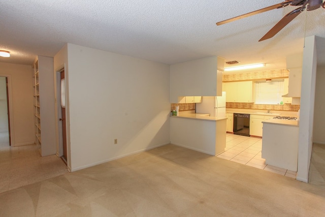 1900 Goliad St, Big Spring, TX 79720 - kitchen featuring black dishwasher, freestanding refrigerator, a ceiling fan, light colored carpet, and a peninsula