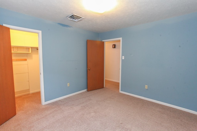 1900 Goliad St, Big Spring, TX 79720 - unfurnished bedroom featuring a walk in closet, a closet, carpet floors, baseboards, and a textured ceiling