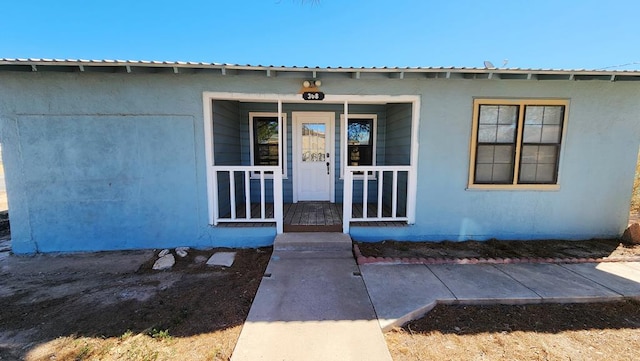 doorway to property featuring metal roof and a porch