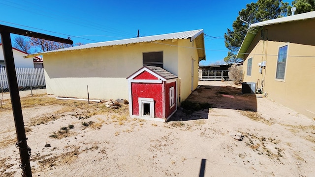 exterior space with an outbuilding, fence, cooling unit, and stucco siding