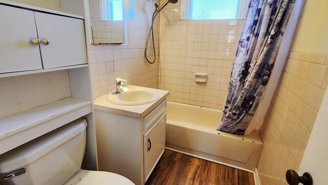 full bath featuring tile walls, toilet, shower / bath combo with shower curtain, vanity, and wood finished floors