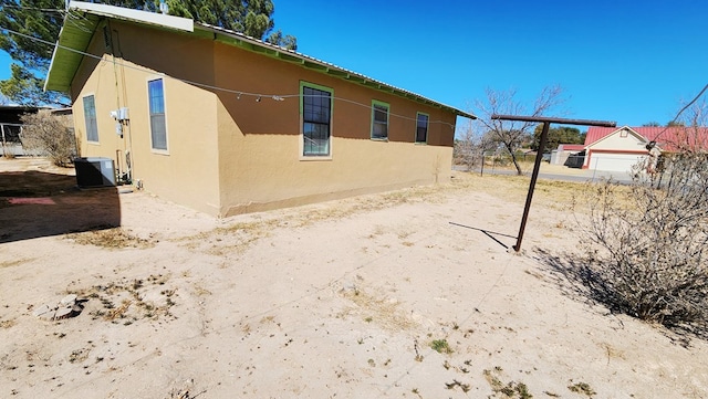 view of side of home featuring cooling unit and stucco siding