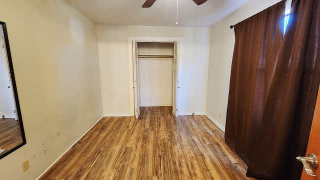 unfurnished bedroom featuring a closet, ceiling fan, baseboards, and wood finished floors