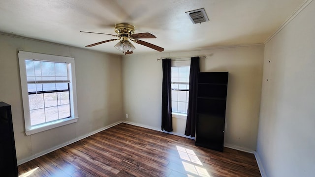 spare room featuring a wealth of natural light, baseboards, visible vents, and wood finished floors