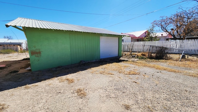 view of outbuilding featuring driveway, fence, and an outdoor structure