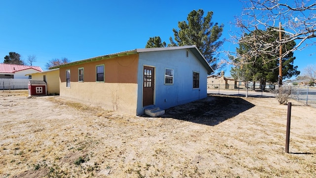 view of side of property with entry steps, fence, and stucco siding