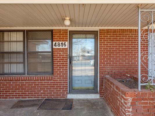 doorway to property featuring brick siding