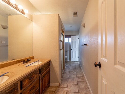 full bathroom with double vanity, a sink, visible vents, and baseboards