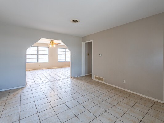 empty room with light tile patterned floors, baseboards, visible vents, and a ceiling fan