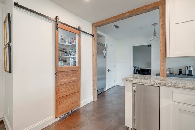 2602 N L St, Midland, TX 79705 - kitchen with a barn door, white cabinetry, light stone counters, built in refrigerator, and baseboards
