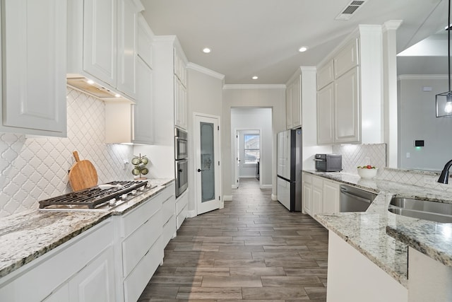 kitchen with sink, white cabinetry, stainless steel appliances, light stone countertops, and ornamental molding