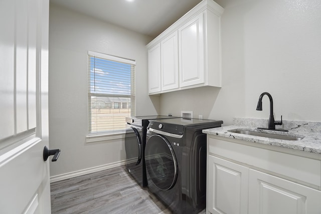 laundry room with washer and dryer, sink, cabinets, and light hardwood / wood-style floors