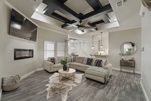 living room with hardwood / wood-style flooring, ceiling fan, coffered ceiling, ornamental molding, and beamed ceiling