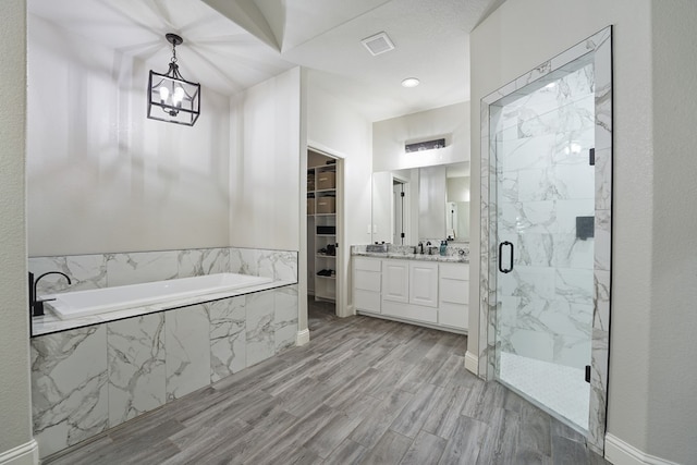 bathroom featuring vanity, independent shower and bath, wood-type flooring, and a notable chandelier