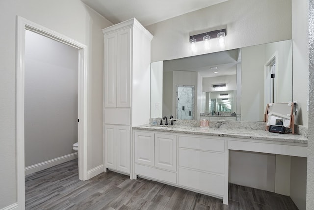 bathroom with vanity, toilet, hardwood / wood-style floors, and a shower