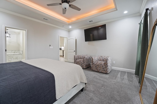 carpeted bedroom featuring a raised ceiling, ornamental molding, ceiling fan, and ensuite bath