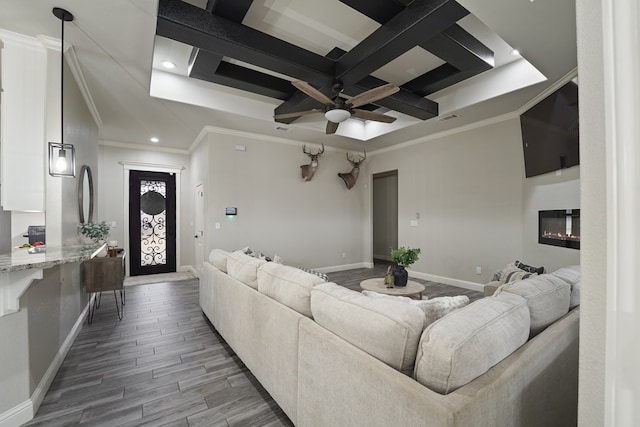 living room featuring coffered ceiling, hardwood / wood-style flooring, ornamental molding, and ceiling fan