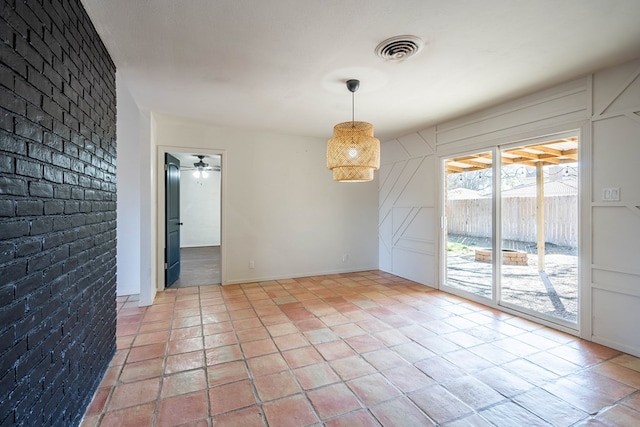 spare room featuring brick wall, visible vents, and a ceiling fan