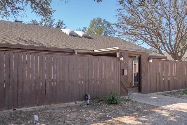 exterior space featuring fence and roof with shingles