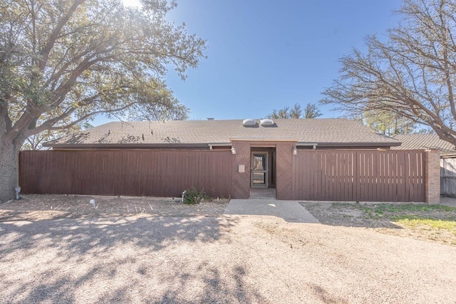 view of front of home featuring roof with shingles and fence