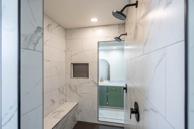 bathroom with vanity, a tile shower, and tile walls