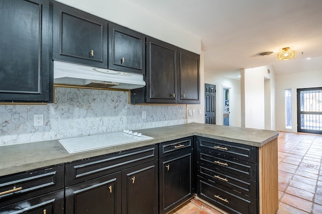 kitchen featuring under cabinet range hood, a peninsula, visible vents, dark cabinetry, and white electric cooktop