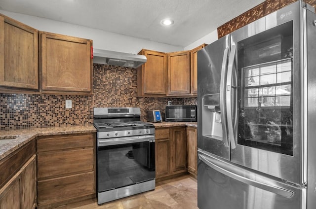 2401 Morrison Dr, Big Spring, TX 79720 - kitchen with backsplash, range hood, light stone countertops, stainless steel appliances, and brown cabinetry