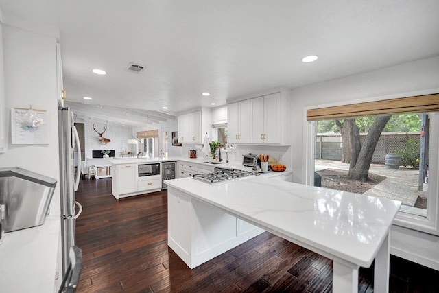907 Harvard Ave, Midland, TX 79701 - kitchen with a peninsula, stainless steel gas cooktop, wine cooler, black microwave, and recessed lighting