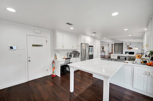 907 Harvard Ave, Midland, TX 79701 - kitchen with appliances with stainless steel finishes, a peninsula, white cabinetry, dark wood-style flooring, and recessed lighting