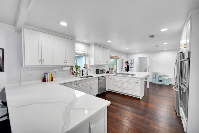 907 Harvard Ave, Midland, TX 79701 - kitchen with a peninsula, stainless steel appliances, a sink, white cabinetry, and dark wood-style flooring