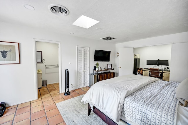 907 Harvard Ave, Midland, TX 79701 - bedroom with a skylight, light tile patterned floors, ensuite bath, a closet, and baseboards
