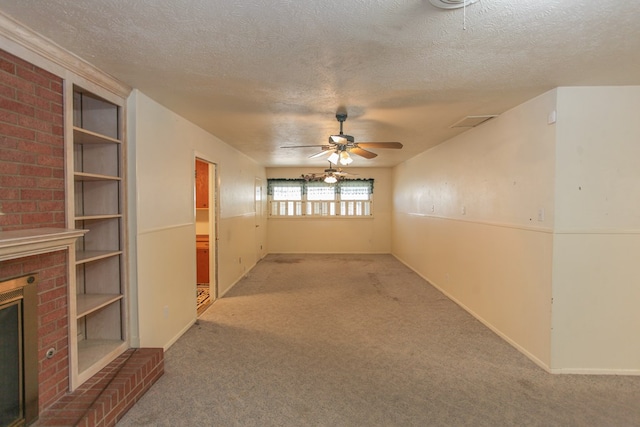 unfurnished room featuring ceiling fan, a fireplace, carpet floors, and a textured ceiling