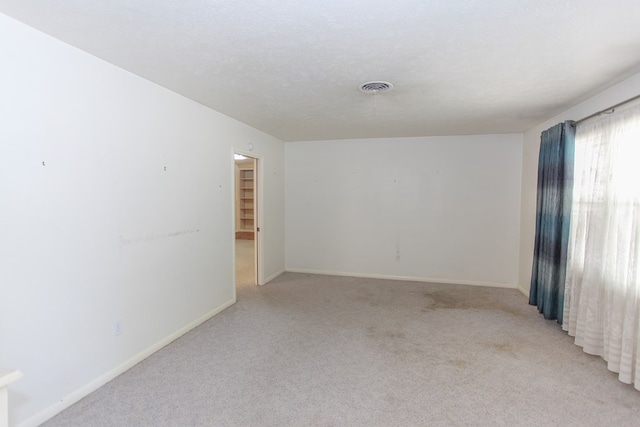 carpeted empty room featuring a textured ceiling