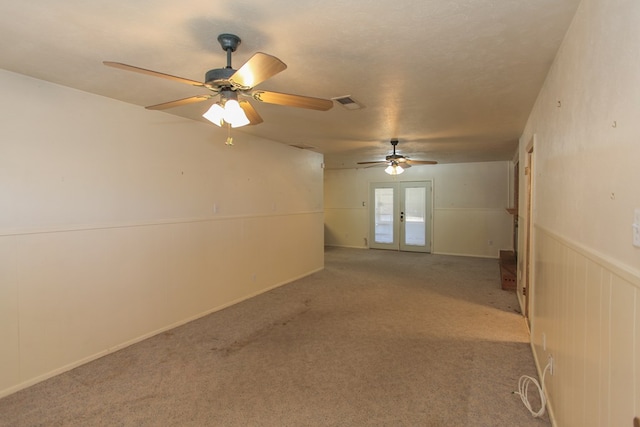 empty room featuring ceiling fan, french doors, light colored carpet, and a textured ceiling