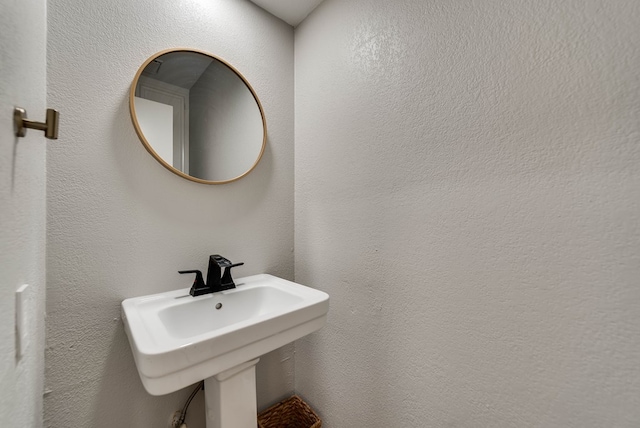 bathroom featuring a sink and a textured wall