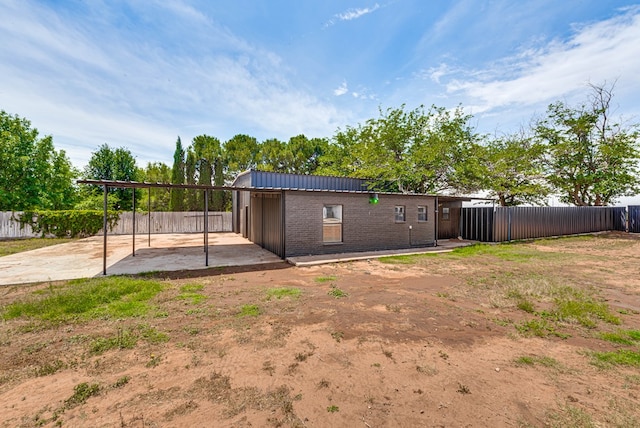 back of house with a patio area, a fenced backyard, a carport, and brick siding