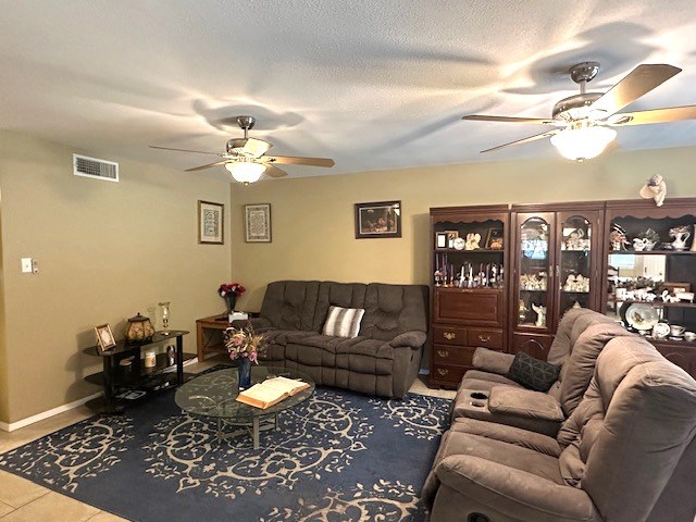 living area with visible vents, tile patterned flooring, baseboards, and ceiling fan