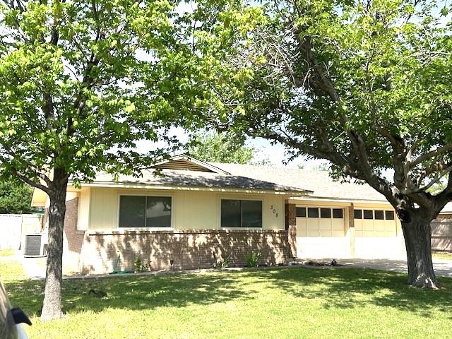 view of front of home featuring a front lawn, cooling unit, fence, brick siding, and an attached garage