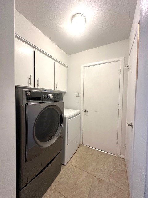 washroom featuring washing machine and dryer, a textured ceiling, and cabinet space