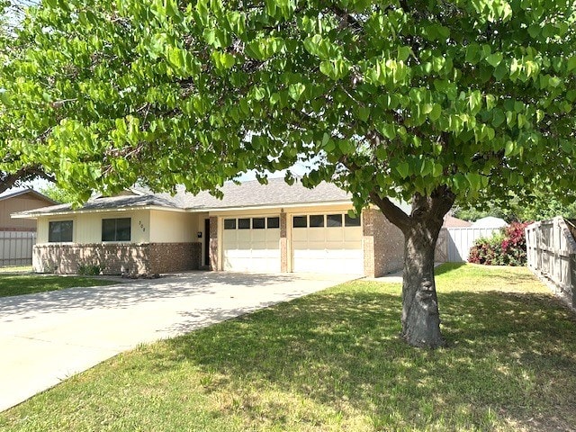 view of front of home with driveway, fence, a garage, brick siding, and a front yard