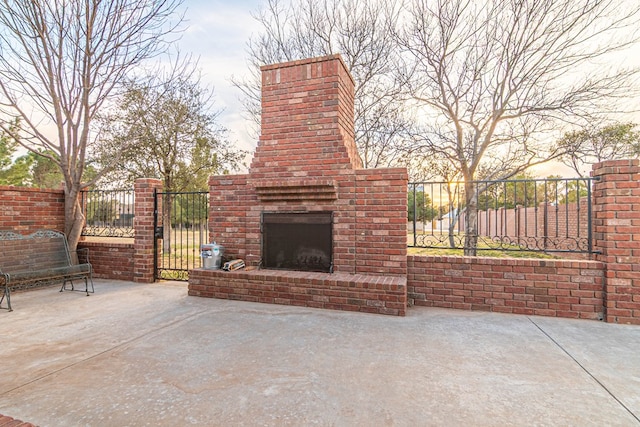 view of patio / terrace featuring an outdoor brick fireplace and fence