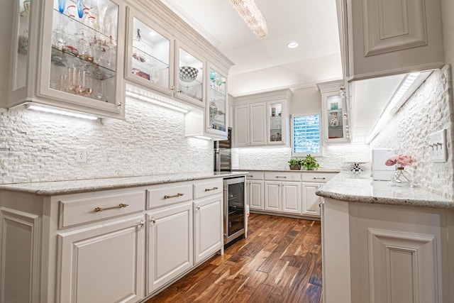 kitchen with wine cooler, dark wood-type flooring, backsplash, white cabinetry, and light stone counters