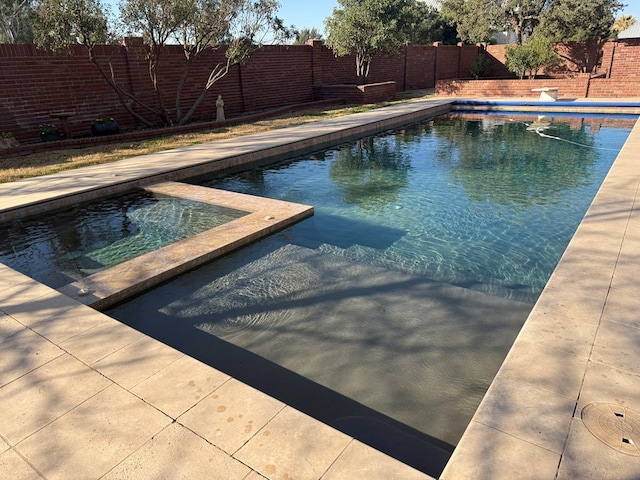 view of pool with a fenced backyard, a pool with connected hot tub, and a patio