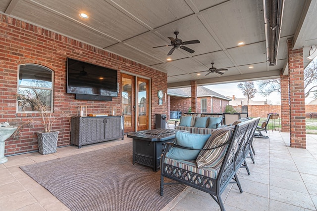 view of patio / terrace with a ceiling fan and an outdoor living space with a fire pit