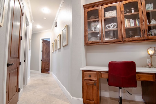 office featuring crown molding, built in desk, and baseboards