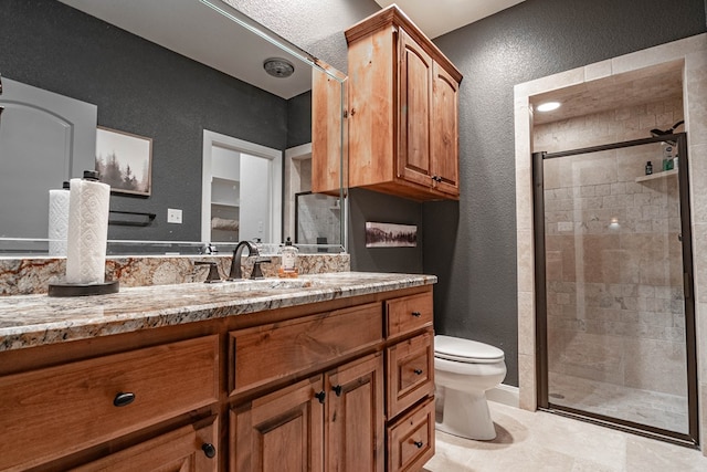 full bathroom featuring a textured wall, a stall shower, toilet, and vanity