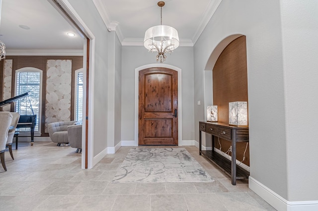 entrance foyer featuring baseboards, ornamental molding, and an inviting chandelier